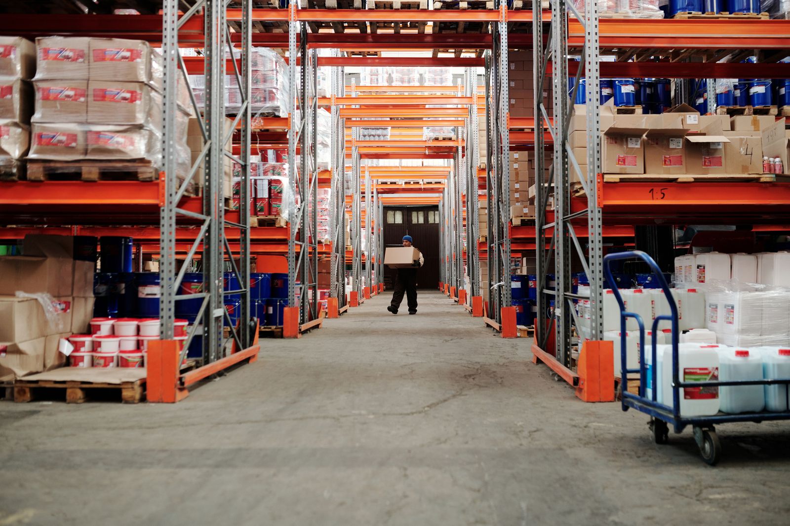 Warehouse worker carrying a carton between storage racks